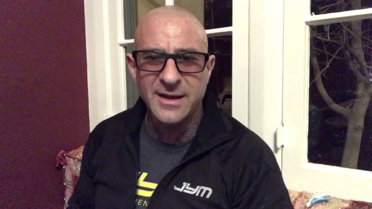 Dr. Jim Stoppani in glasses and black JYM jacket speaking to camera indoors for Creatine Research Exposed article.
