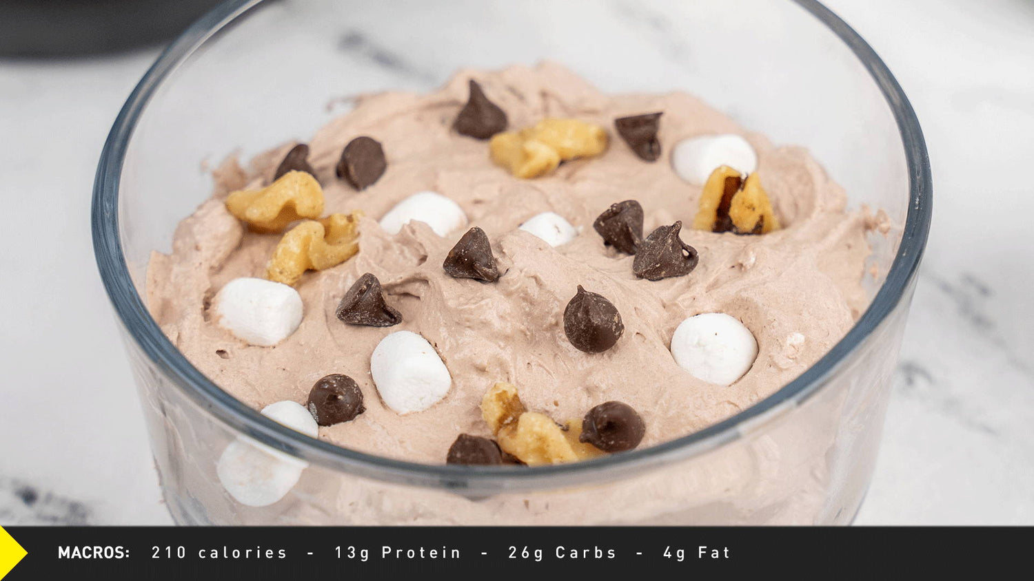 Glass bowl of Rocky Road Pro JYM ice cream with chocolate chips, marshmallows, and walnuts; macro panel shows 210 calories.