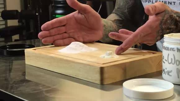 Tattooed hands gesturing over white supplement powder on a wooden cutting board, illustrating "Say No to Concentrates".